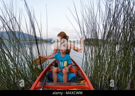 Mother and son paddling in a canoe on a picturesque lake at dusk Stock Photo