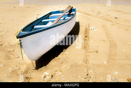 Small white row boat on a beach near the water edge. Stock Photo