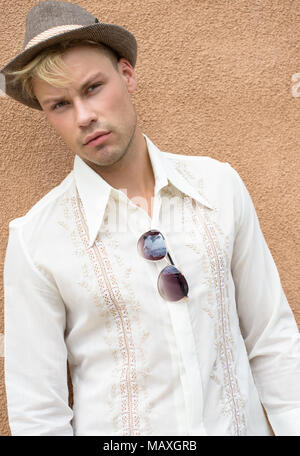 A Caucasian man, male model posing wearing men's 70s vintage shirt and hat, a men's vintage fashion editorial concept. Stock Photo