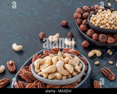 Background of nuts - cashew, pecan, pine nuts, hazelnuts - on dark blue background with copy space. Stock Photo