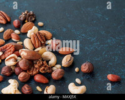 Background of nuts - cashew, pecan, pine nuts, hazelnuts - on dark blue background with copy space. Top view or flat lay Stock Photo