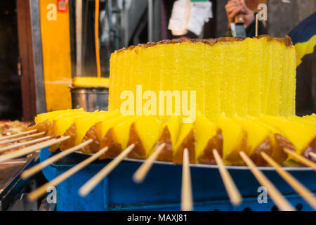 Sweet Brightly Colored Yellow Cake at Traditional Chinese Market with Sticks Stock Photo