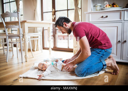 Father changing a baby girl at home. Stock Photo