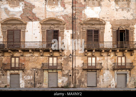 The facade of a building in Palermo, Sicily, Italy. Intricate detailed architecture and plaster rendering that has weathered over time revealing the b Stock Photo
