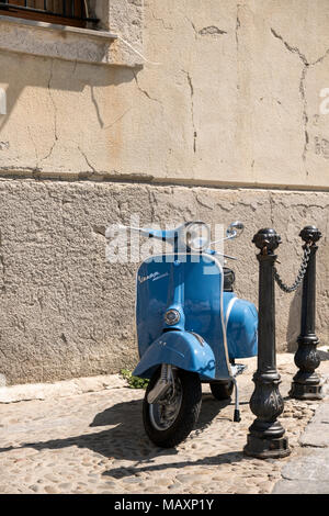 A modern sky blue Vespa Sprint scooter parked near the harbour at Cefalu in Sicily, Italy. Stock Photo