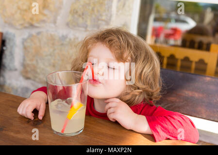 Small child drinking through a plastic straw, Spain Stock Photo