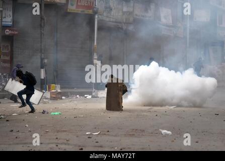 April 5, 2018 - Srinagar, J&K, India - A tear gas shell fired by Indian policemen explodes near Kashmiri students in Srinagar, Indian administered Kashmir. Fierce clashes broke out between government forces and students in Srinagar on Thursday as the valley continued to remain tense over the killing of 17 people including 13 militants and 4 civilians in separate encounters in south Kashmir. Police used tear smoke shells to chase away the protesters. The violence rocked Kashmir valley on the day when authorities lifted restrictions after four days of the shutdown. (Credit Image: © Saqib Majeed/ Stock Photo