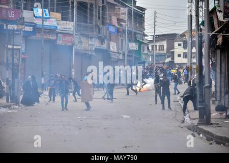 April 5, 2018 - Srinagar, J&K, India - A tear gas shell fired by Indian policemen explodes near Kashmiri students during clashes in Srinagar, Indian administered Kashmir. Fierce clashes broke out between government forces and students in Srinagar on Thursday as the valley continued to remain tense over the killing of 17 people including 13 militants and 4 civilians in separate encounters in south Kashmir. Police used tear smoke shells to chase away the protesters. The violence rocked Kashmir valley on the day when authorities lifted restrictions after four days of the shutdown. (Credit Image: Stock Photo