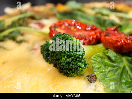 French opened pie quiche with tuna / chicken, broccoli, spinach, pepper, eggs, cheese and dried tomato. Close up. Stock Photo