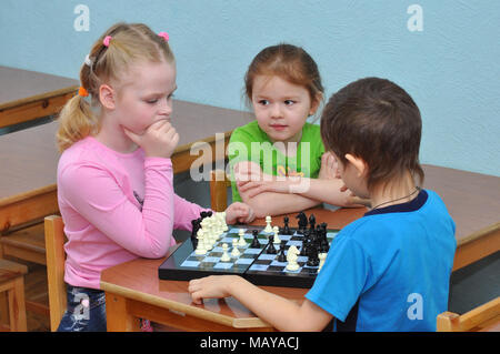 Gadjievo, Russia - April 21, 2011: Children play chess at a table in a kindergarten group Stock Photo