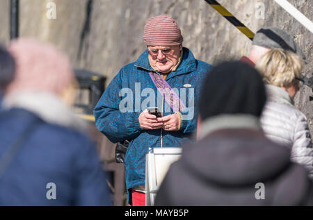 Middle aged or elderly man standing outside texting on a mobile phone in the UK. Senior using technology, sending text. Stock Photo