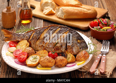 Roasted dorada fish with vegetables on wooden background Stock Photo