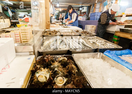 Tokyo, Japan. Early morning in Tsukiji Fish Market. Workers laying out fresh fish and seafood on the counter. Stock Photo