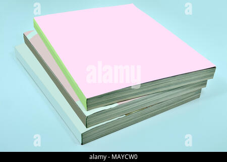 Stack of three thick magazines or books, catalogs with a blank pink soft cover on a blue background - a mock up for demonstrating your design Stock Photo