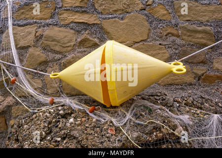 Yellow buoy on a wall with fishnet Stock Photo