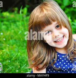 Happy blond 4 years girl smiling on the camera, front view portrait, selective focus Stock Photo