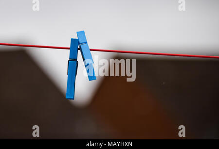 A pair of blue plastic clothes pegs on a red clothes line Stock Photo