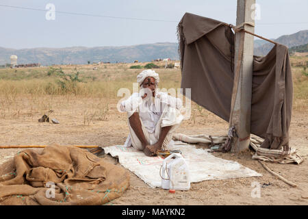 Man smoking in white traditional dress and a white turban at the Pushkar Camel Fair, Rajasthan, India. Stock Photo