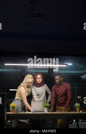 Three businesspeople having discussion over laptop in office Stock Photo