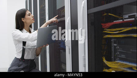 Technician performing maintenance tasks in a server room rack Stock Photo