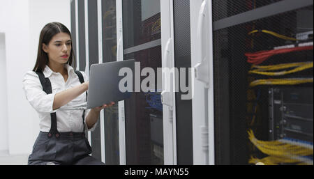 Technician performing maintenance tasks in a server room rack Stock Photo