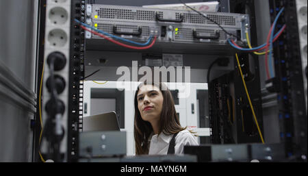 Technician performing maintenance tasks in a server room rack Stock Photo