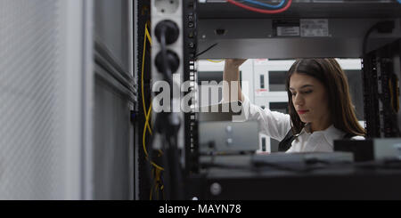 Technician performing maintenance tasks in a server room rack Stock Photo