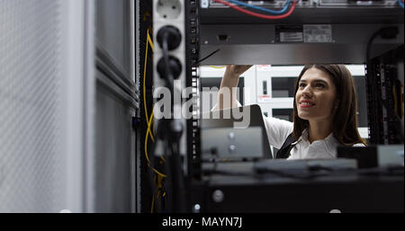 Technician performing maintenance tasks in a server room rack Stock Photo