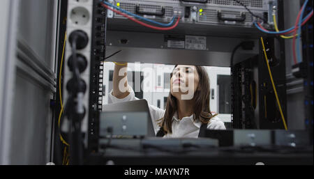 Technician performing maintenance tasks in a server room rack Stock Photo