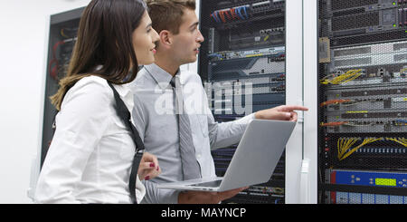 Technicians using laptop while analyzing server in server room Stock Photo