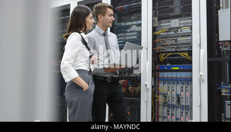 Technicians using laptop while analyzing server in server room Stock Photo