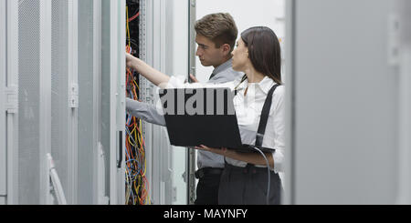 Technicians using laptop while analyzing server in server room Stock Photo