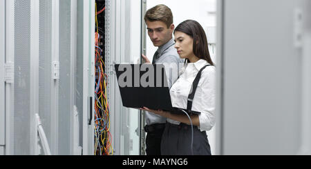 Technicians using laptop while analyzing server in server room Stock Photo