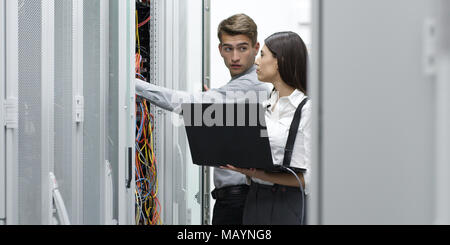 Technicians using laptop while analyzing server in server room Stock Photo