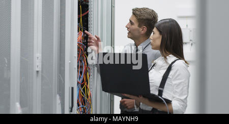 Technicians using laptop while analyzing server in server room Stock Photo