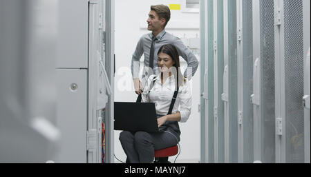 Technicians using laptop while analyzing server in server room Stock Photo