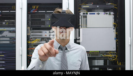 young IT engeneer using virtual reality headset over server room background Stock Photo