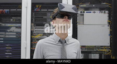 young IT engeneer using virtual reality headset over server room background Stock Photo