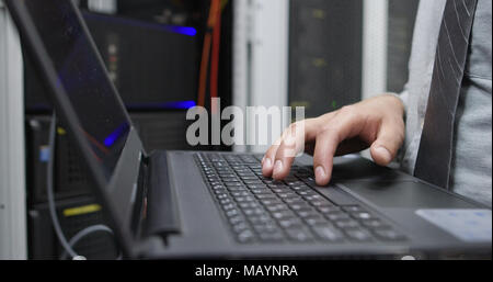 IT data specialist working on laptop on maintaining server rack Stock Photo