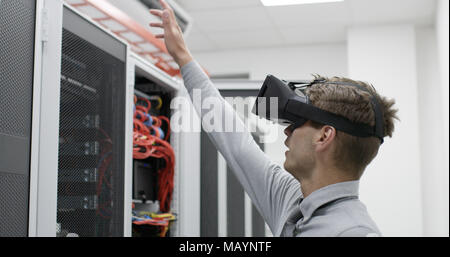 young IT engeneer using virtual reality headset over server room background Stock Photo