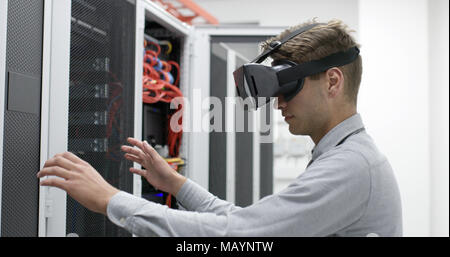 young IT engeneer using virtual reality headset over server room background Stock Photo