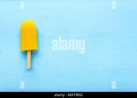 Orange popsicle on blue wooden background. Summer refreshing icecream with natural juice Stock Photo
