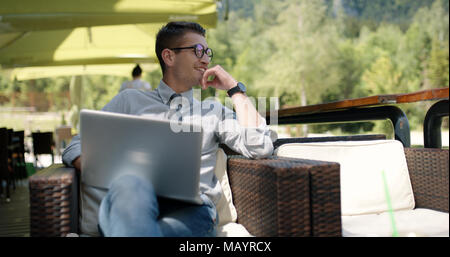 Young businessman casually dressed working outside in caffe bar. Stock Photo