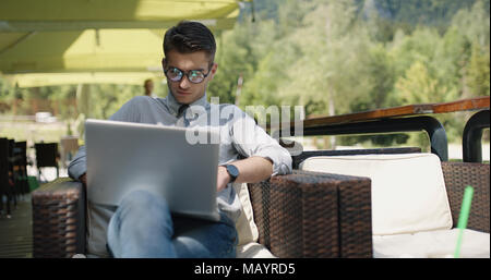 Young businessman casually dressed working outside in caffe bar. Stock Photo