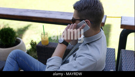 Young businessman casually dressed working outside in caffe bar. Stock Photo