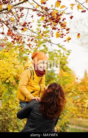 Happy Autumn Family in Fall Park Outdoors. Happy Mother and Child Boy having Fun Stock Photo