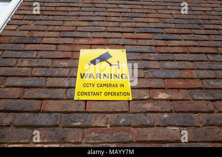 Warning CCTV cameras in constant operation sign on brick wall, UK Stock Photo