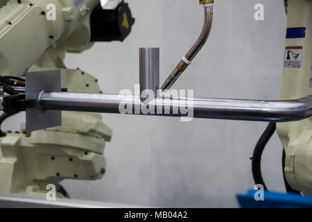 Robot arm welding pipe ; focus at torch Stock Photo