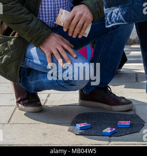 Con artists performing Shell Game scam to suspecting victims using matchsticks and small paper ball. The aim of the game is to predict in which box the ball will end up Stock Photo