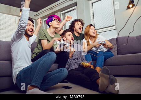 A group of friends playing video games sitting on the couch,  in Stock Photo